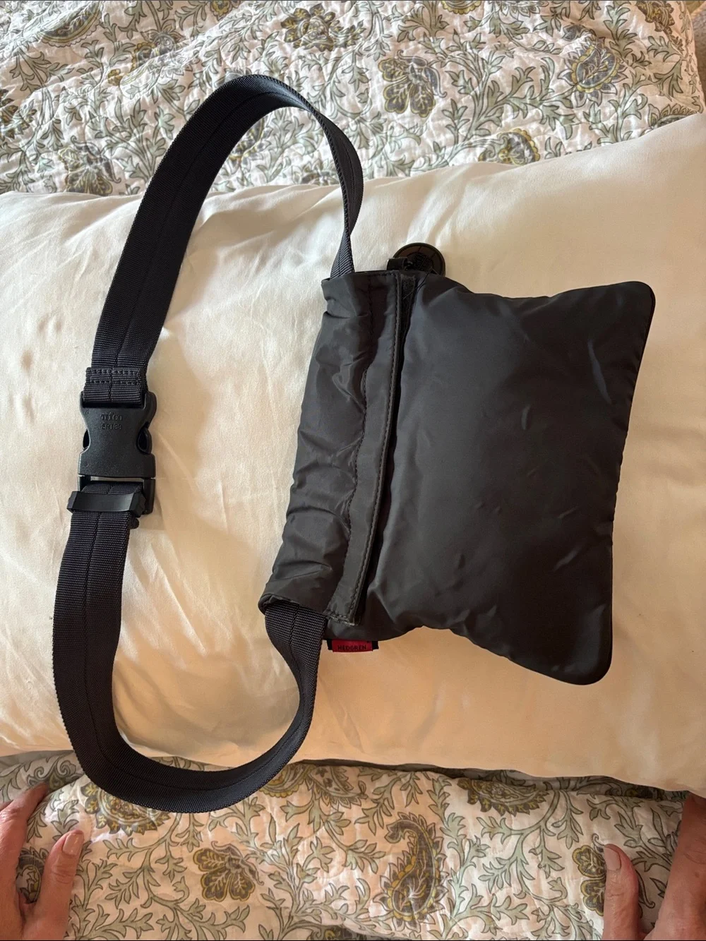This grey Hedgren crossbody bag features a distinctive red label showcasing the